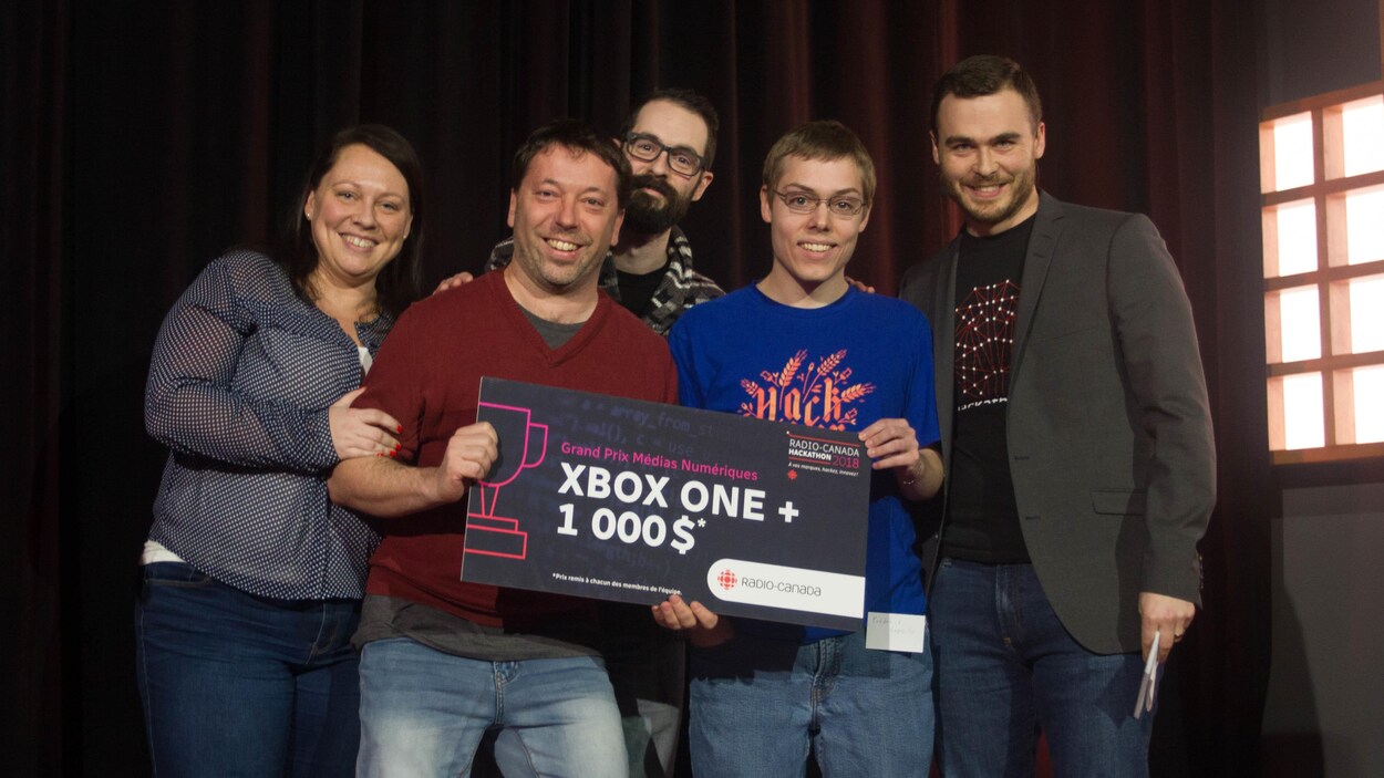 Une photo de Marie-Ève Pageau, Éric Letarte, Jean-Sébastien Daigle, Frédérick Capovilla et Maxime St-Pierre. Éric Letarte et Frédérick Capovilla tiennent une affiche sur laquelle ont peut lire « Grand prix Médias numériques, Xbox One + 1000 $ ». Une photo de Marie-Ève Pageau, Éric Letarte, Jean-Sébastien Daigle, Frédérick Capovilla et Maxime St-Pierre. Éric Letarte et Frédérick Capovilla tiennent une affiche sur laquelle ont peut lire « Grand prix Médias numériques, Xbox One + 1000 $ ».