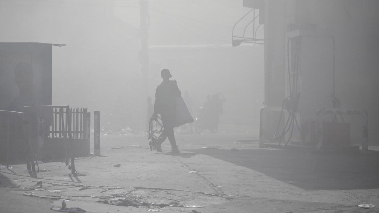 Un homme se promène dans la rue sous une épaisse fumée reliée aux manifestations.