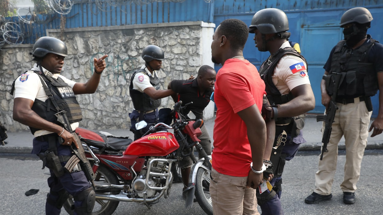 Les policiers passent les menottes à deux hommes près d'une moto.