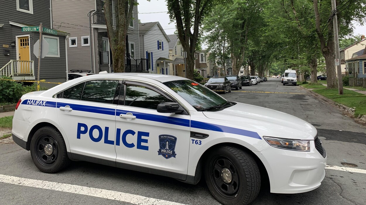 Une voiture et un cordon de la police bloquent la rue.