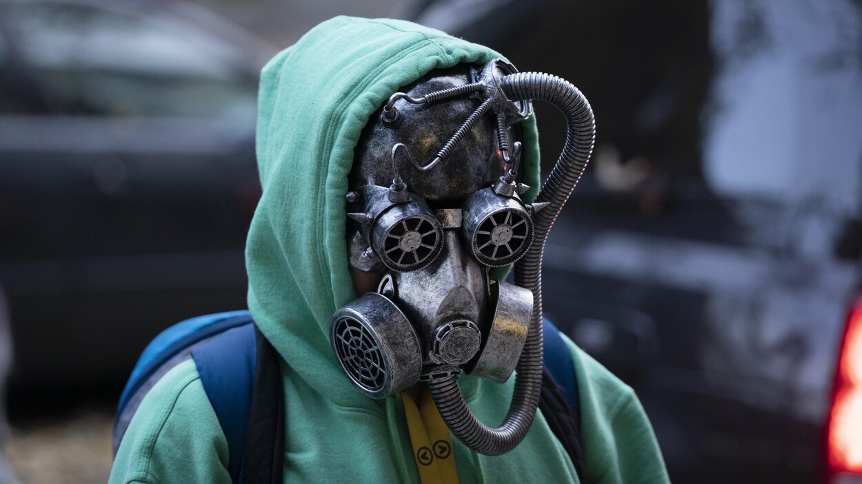 Un adolescent porte un masque à gaz peint en gris qui masque complètement sons visage et lui donne un air de fin du monde.