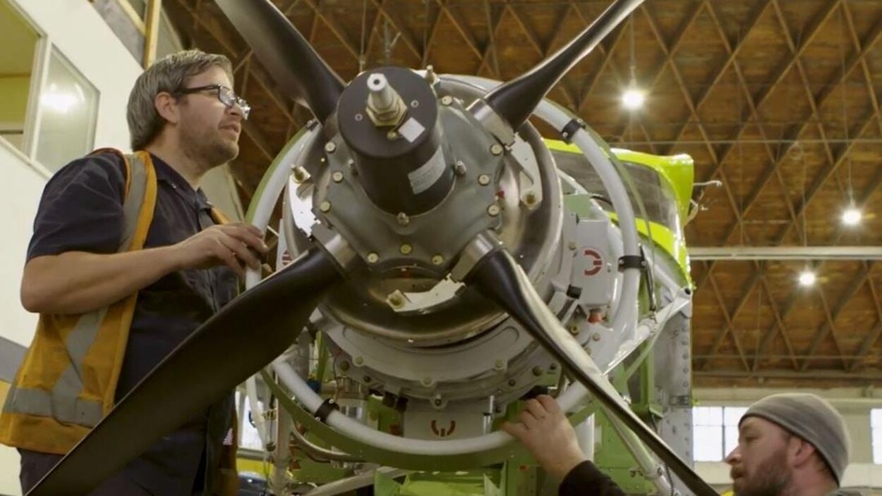 Des techniciens manipulent les hélices d'un moteur d'avion.