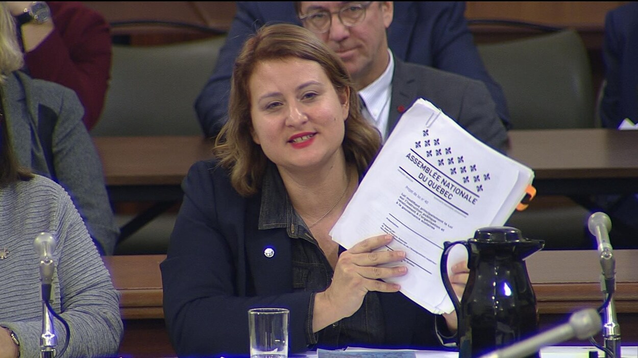 Catherine Harel-Bourdon assise tient dans ses mains une copie du projet de loi 40.