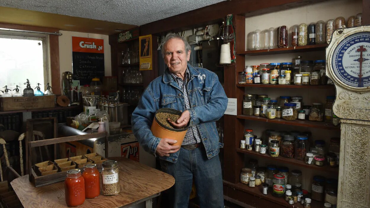 Le conseiller municipal Harold Steves est debout à l'intérieur d'un magasin et tient des graines dans sa main.