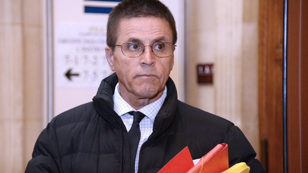 Hassan Diab avec des documents à l'intérieur du palais de justice