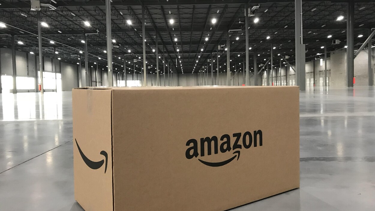 Une boîte portant le logo d'Amazon posée sur le sol d'un entrepôt vide Une boîte portant le logo d'Amazon posée sur le sol d'un entrepôt vide