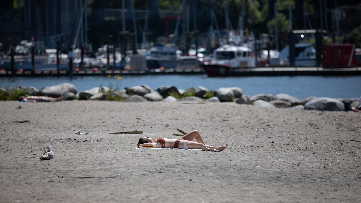 Une femme étendue au soleil sur la plage Sunset à Vancouver.