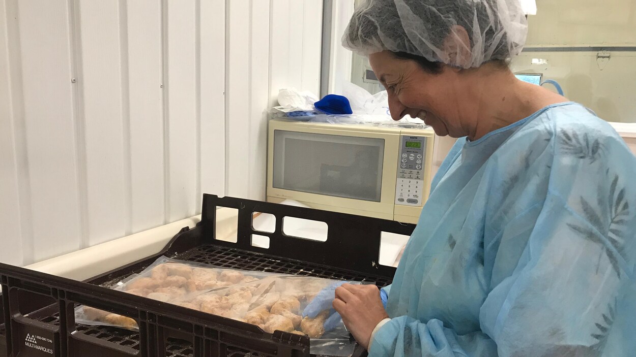 Une femme portant des habits pour assurer la salubrité en cuisine prépare des bouchées de fromage.