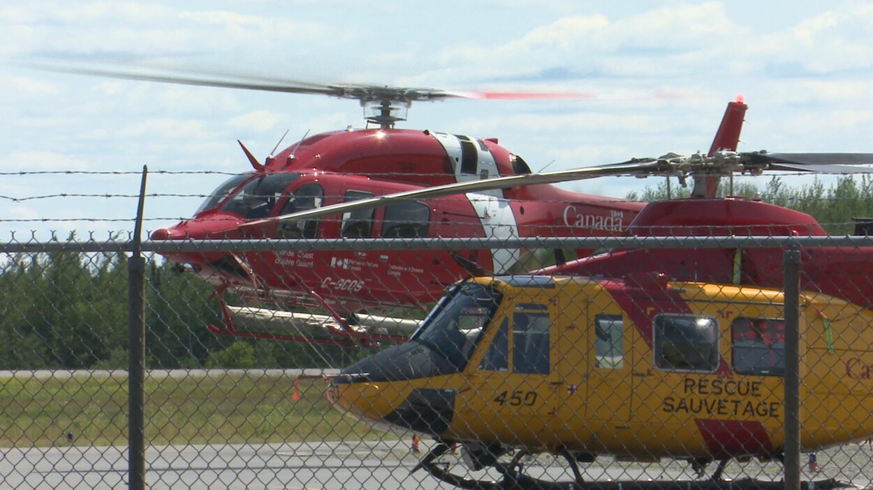Un hélicoptère de la Garde côtière et un hélicoptère de l'Aviation royale canadienne sur une piste d'aéroport.