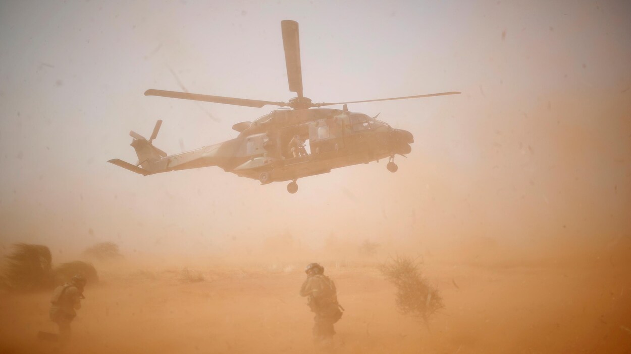 Un hélicoptère décolle au milieu d'une opération désertique.