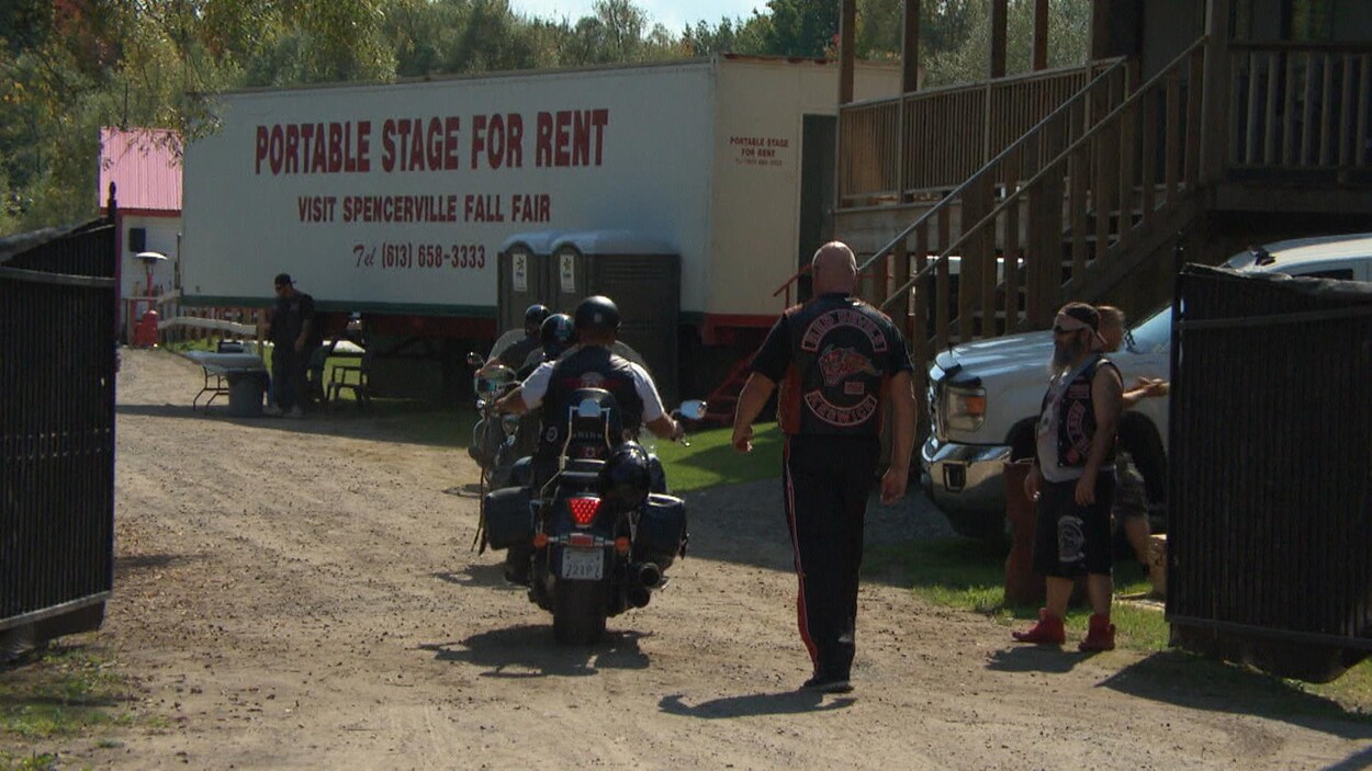 Des hommes à moto et d'autres à pied portant des vestons en cuir avec des logos de groupes de motards. Des hommes à moto et d'autres à pied portant des vestons en cuir avec des logos de groupes de motards.