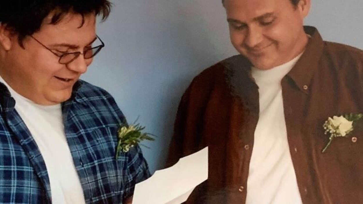Éric Lefebvre lit un texte sur une feuille tandis que Rocky sourit à côté.