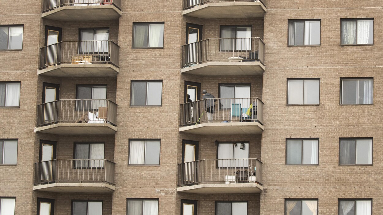 Une femme passe le balai sur son balcon.