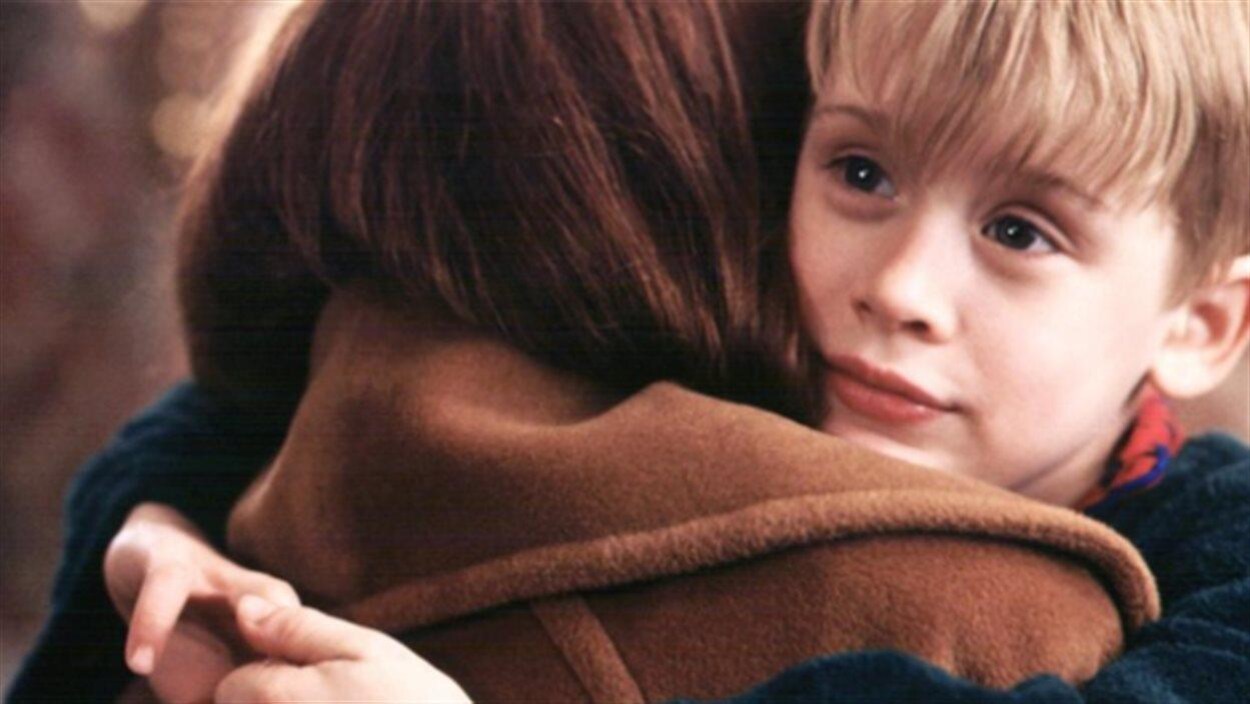 L'enfant est dans les bras d'une adulte.