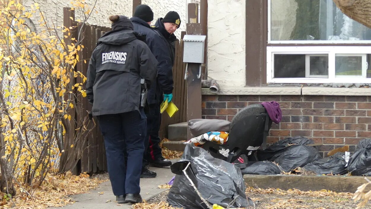Trois policiers sur le point d'entrer dans une maison.