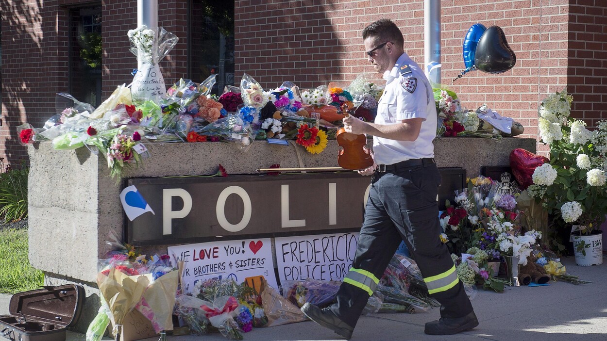 Un paramédic dépose le violon avec lequel il a joué un air en hommage aux policiers morts en service à Fredericton, dans un endroit où de nombreuses gerbes de fleurs ont été placées. Un paramédic dépose le violon avec lequel il a joué un air en hommage aux policiers morts en service à Fredericton, dans un endroit où de nombreuses gerbes de fleurs ont été placées.