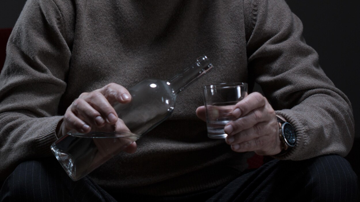 Un homme se verse un verre d'alcool.