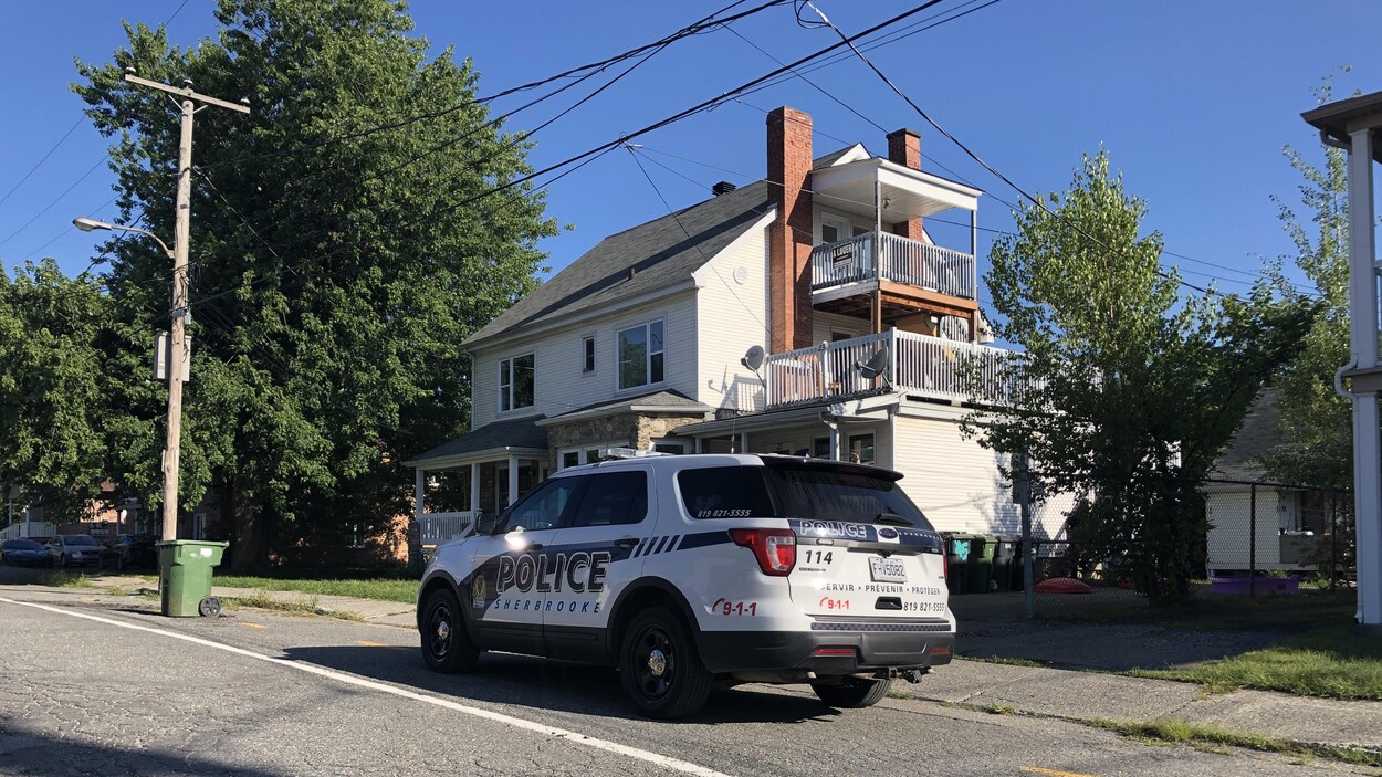 Une voiture de police est stationnée devant une maison.