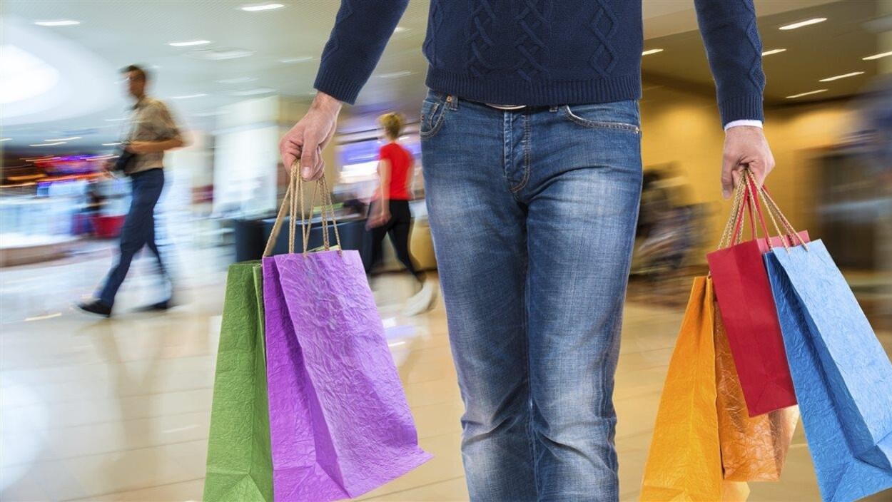 Un homme porte des sacs dans un centre commercial.