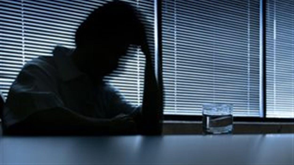Silhouette d'un homme dépressif assis à une table devant une fenêtre.