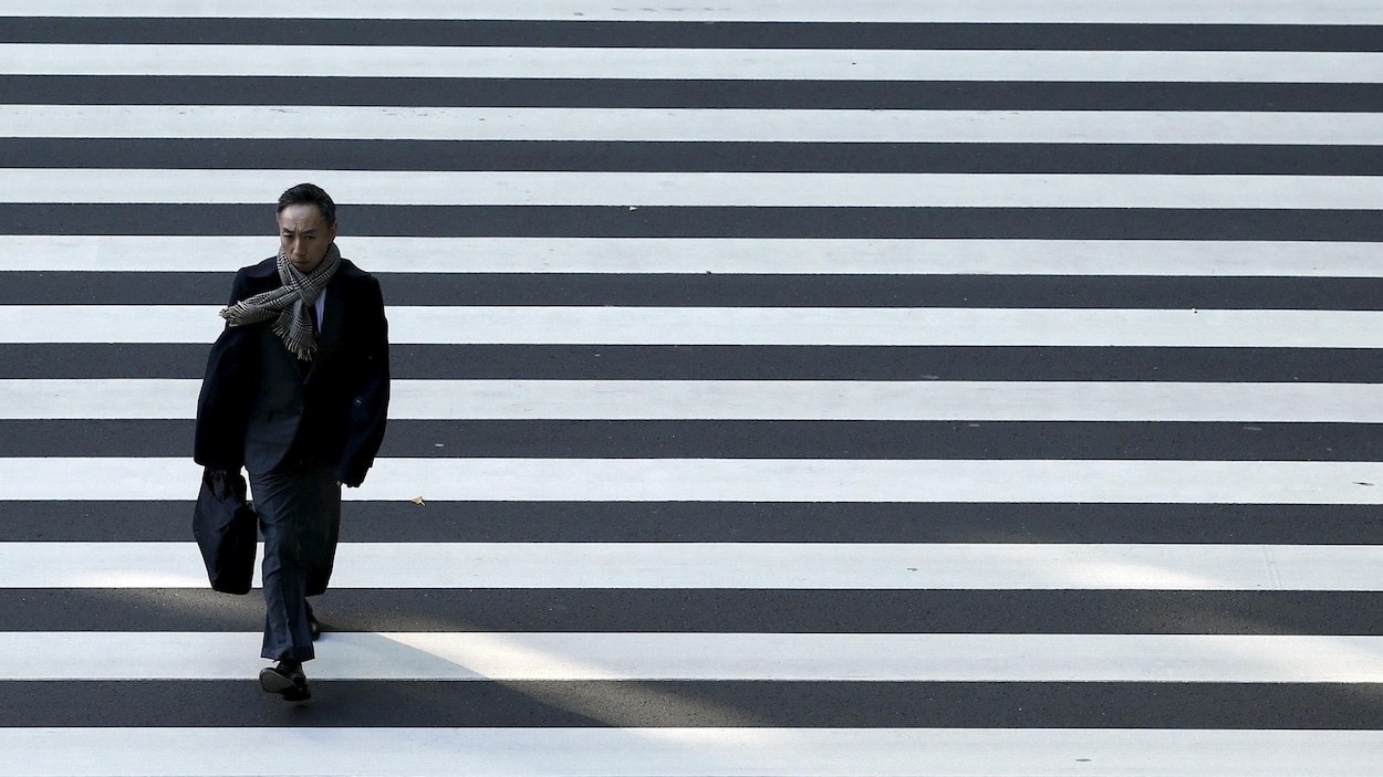 Un homme d'affaires traverse une rue à Tokyo. Un homme d'affaires traverse une rue à Tokyo.