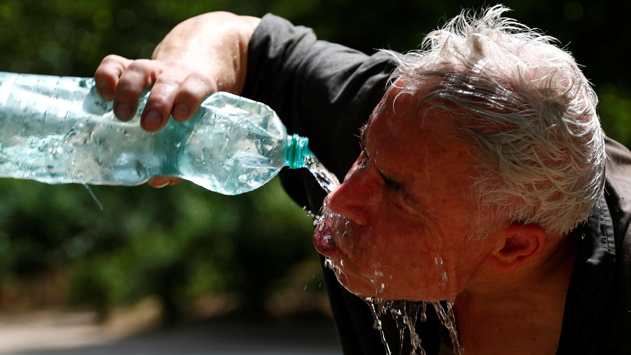 Un homme se rafraîchit avec une bouteille d'eau.