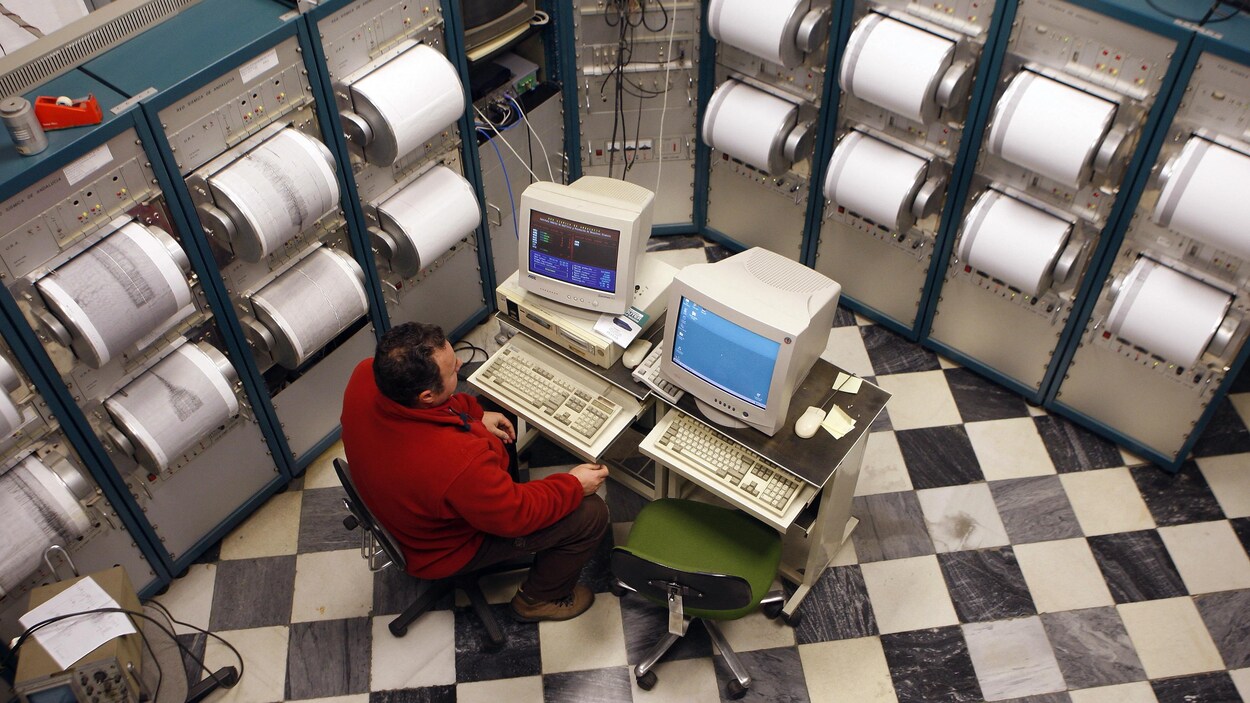 Un homme travaille entouré de sismographes. Un homme travaille entouré de sismographes.