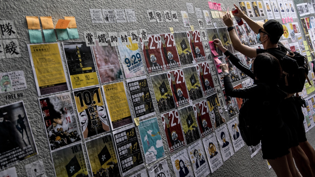Deux manifestants pro-démocratie collent des affiches et des notes autocollantes.