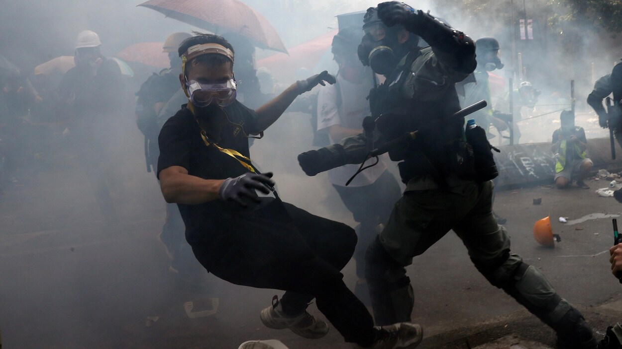 Un protestataire perd l'équilibre lorsqu'il est confronté par un policier antiémeute.