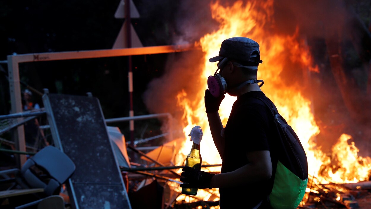 Un manifestant tient un cocktail Molotov alors que des étudiants affrontent la police antiémeute à l'Université chinoise de Hong Kong.