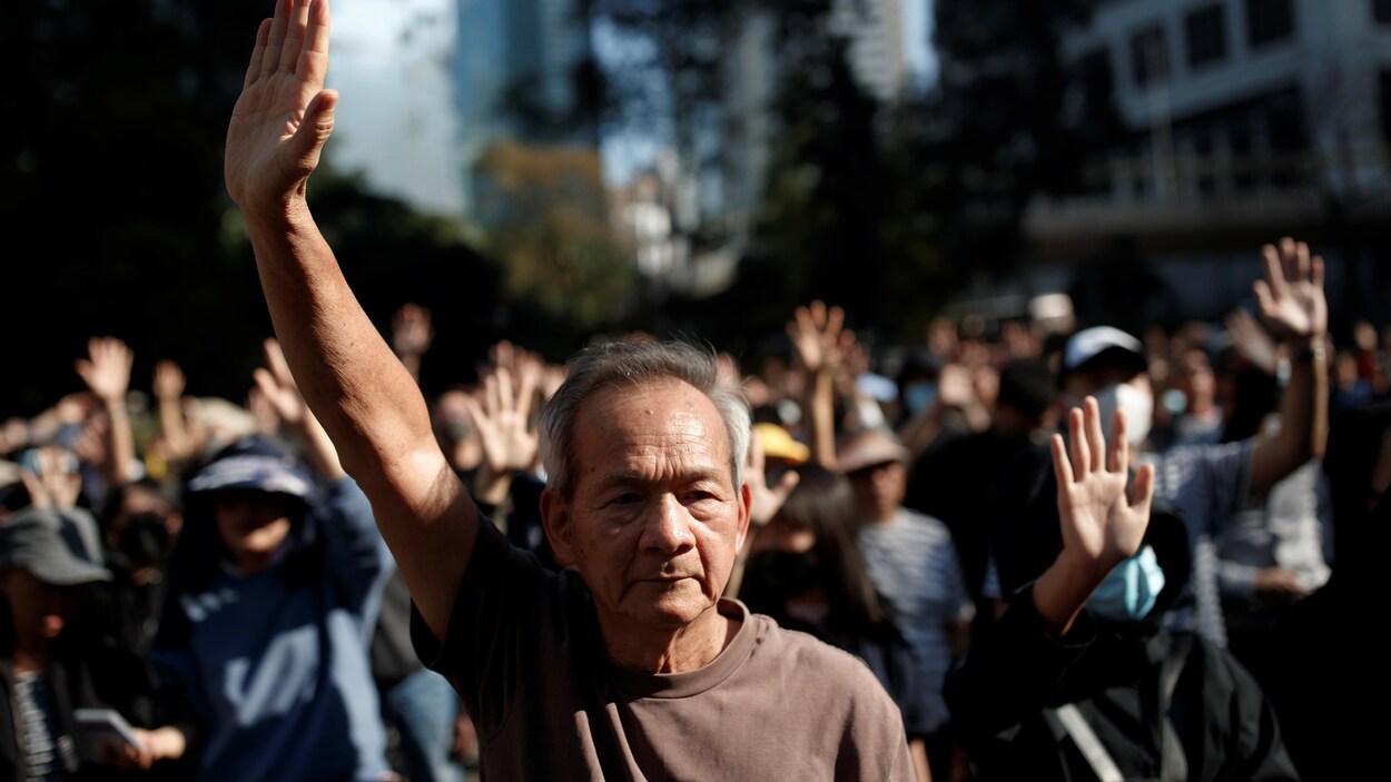 Un retraité hongkongais lève le bras droit lors d'une manifestation avec des étudiants à Hong Kong, le 30 novembre 2019.