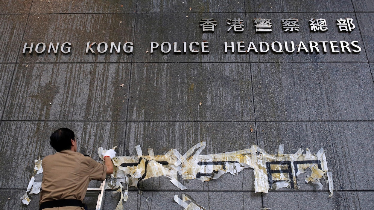 Un employé nettoie la façade vandalisée du quartier général de la police de Hong Hong.