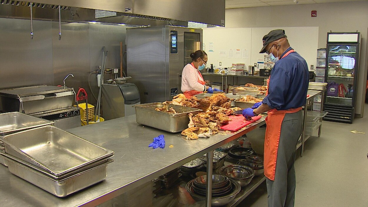 Des bénévoles coupent des poulets dans une cuisine.