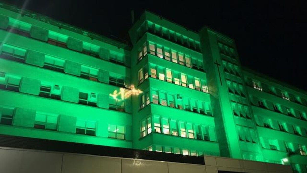 La façade de l'Hôpital d'Alma illuminée en vert.