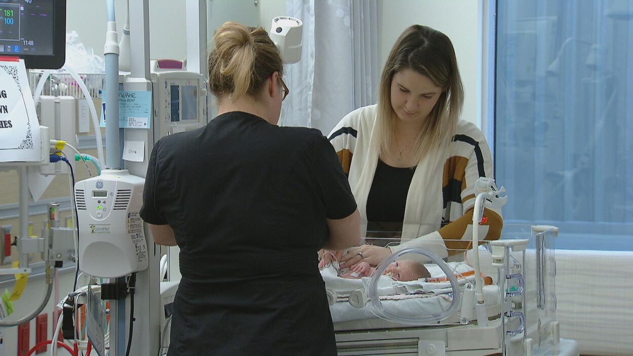 Une infirmière et une femme qui a accouché d'un bébé prématuré sont dans une chambre d'hôpital, debout autour de la couveuse. Une infirmière et une femme qui a accouché d'un bébé prématuré sont dans une chambre d'hôpital, debout autour de la couveuse.