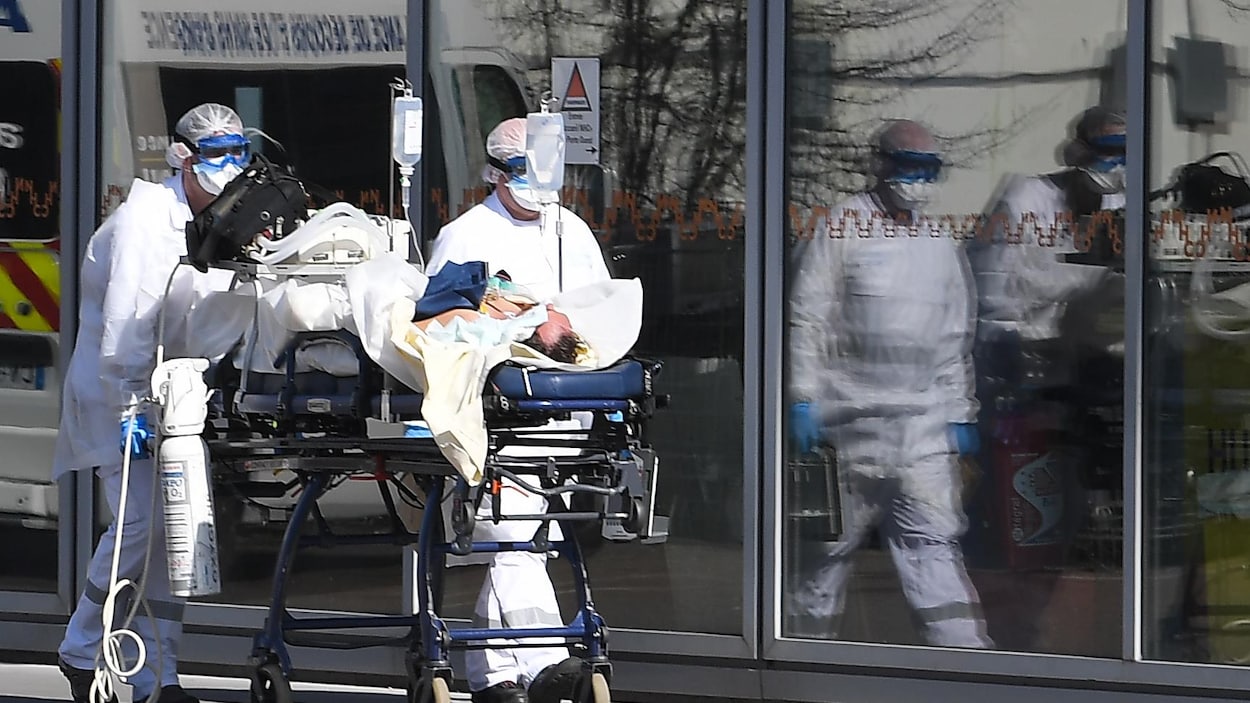 Des infirmiers transportent un patient sous respirateur artificiel.
