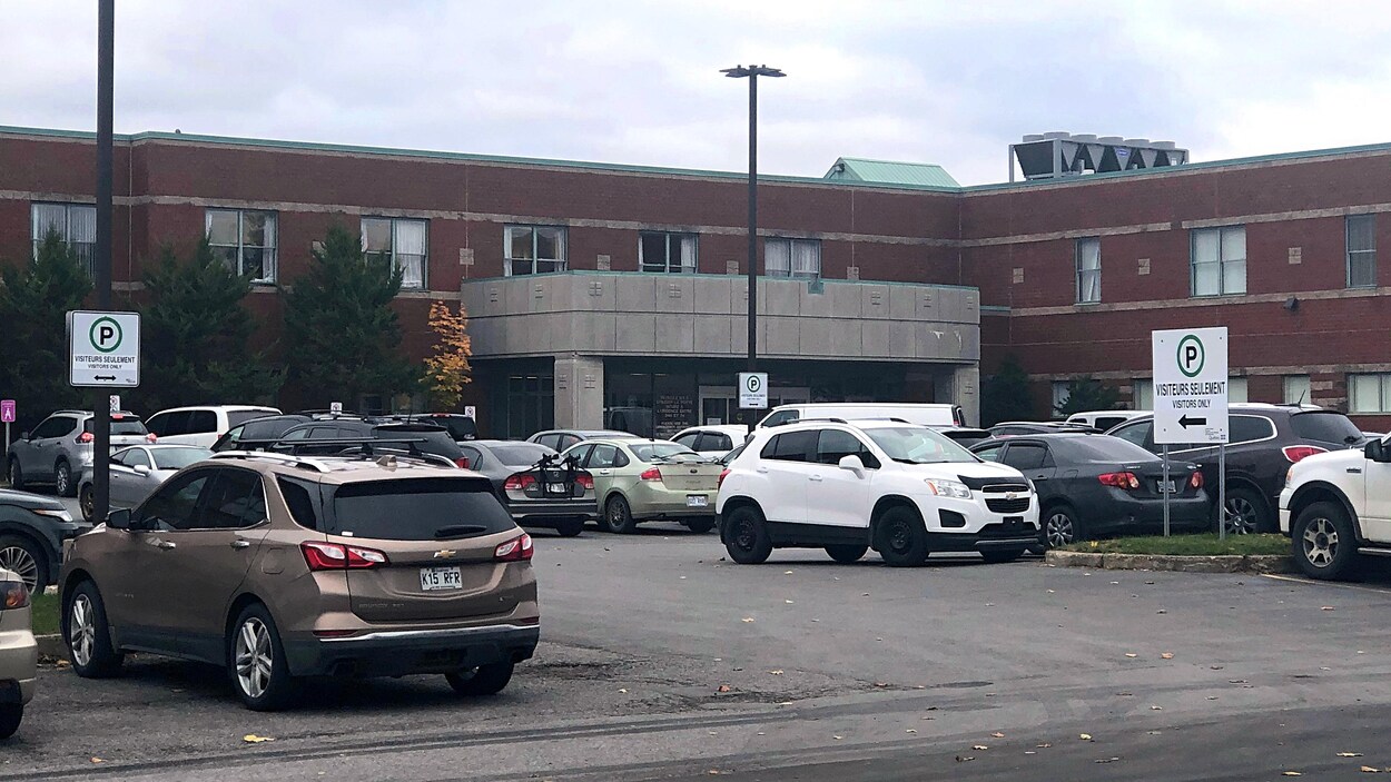 Des véhicules sont stationnés dans l'entrée de l'hôpital.