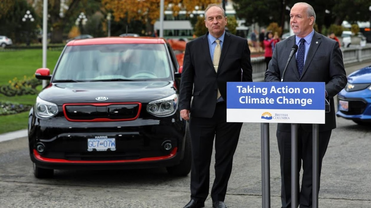 Deux politiciens devant des véhicules électriques.