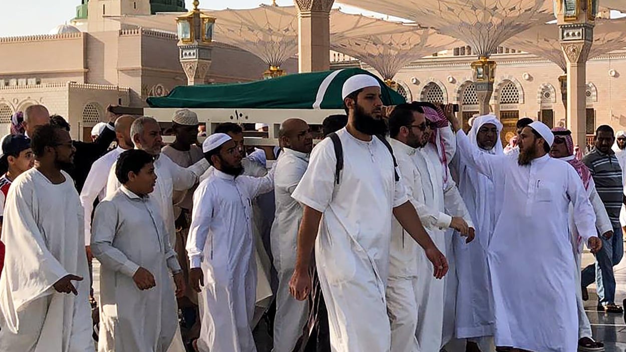 Des hommes vêtus de blanc portent la dépouille de Ben Ali recouverte d'un linceul vert.