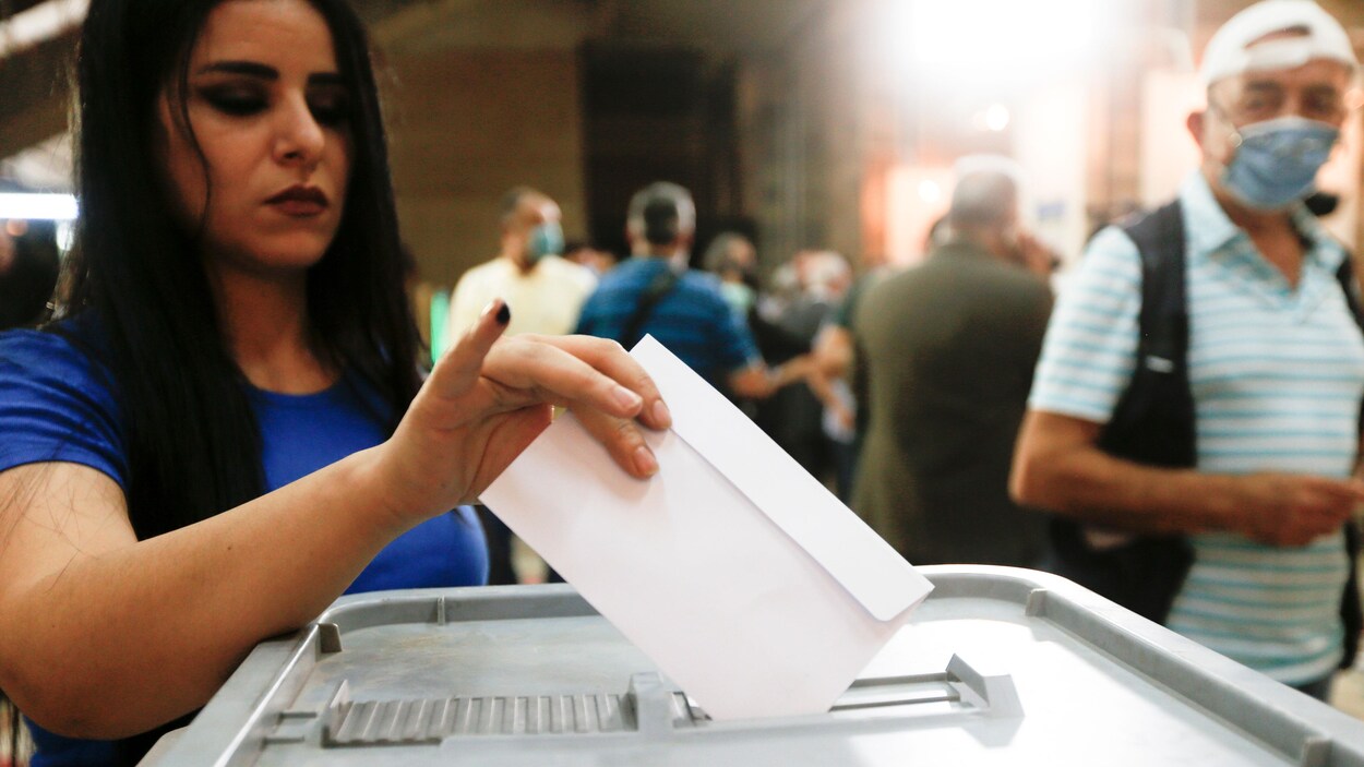 Une femme dépose son bulletin de vote dans l’urne dans un bureau de vote de Damas.