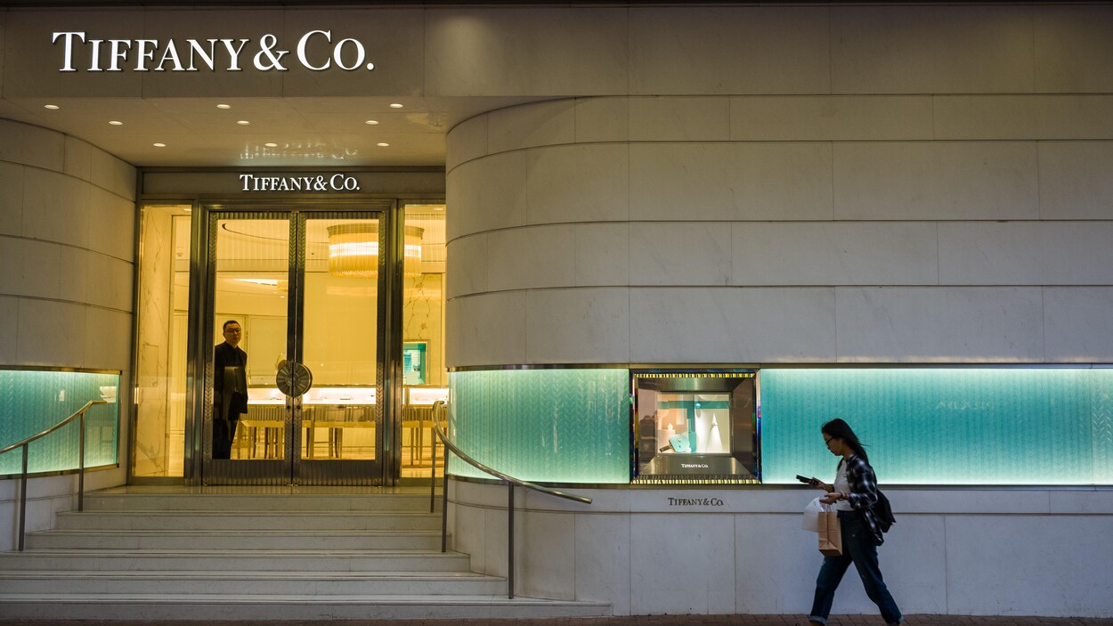Une jeune femme marche devant un magasin Tiffany.