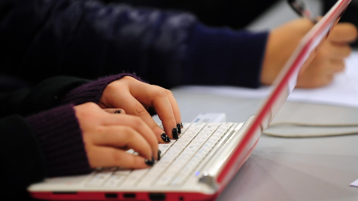Des mains sur un clavier d'ordinateur portable.