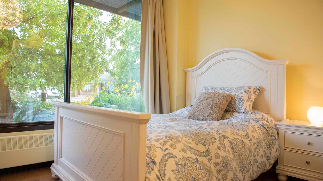 Un lit d'hôtel près d'une baie vitrée.