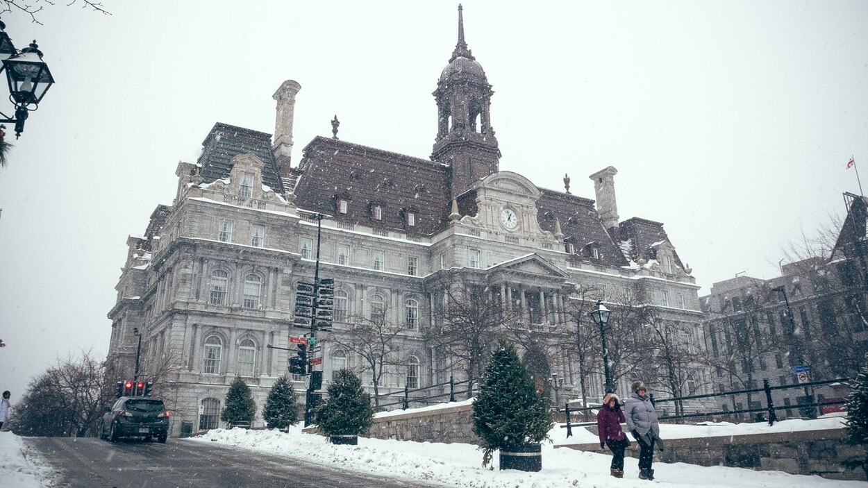 Des gens se baladent sur la place Jacques-Cartier devant l'hôtel de ville de Montréal, alors qu'une fine neige tombe dans le Vieux-Montréal. Des gens se baladent sur la place Jacques-Cartier devant l'hôtel de ville de Montréal, alors qu'une fine neige tombe dans le Vieux-Montréal.