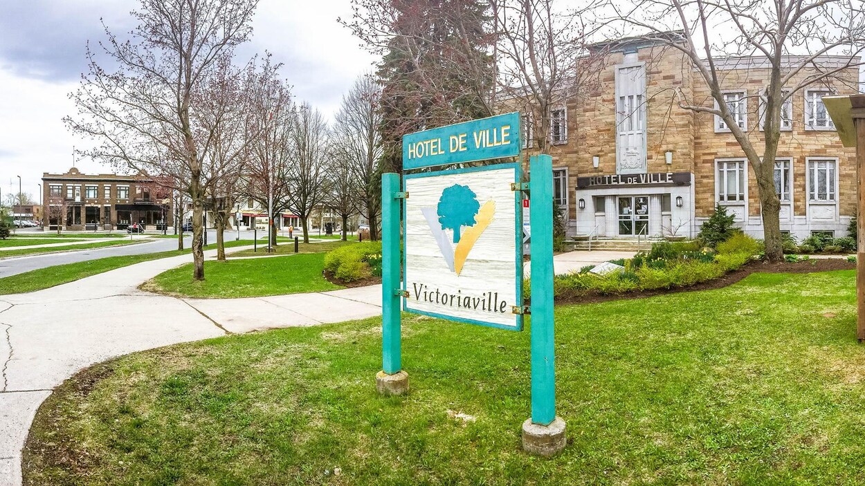 Extérieur de l'hôtel de ville sans feuille dans les arbres avec une affiche indiquant Victoriaville.