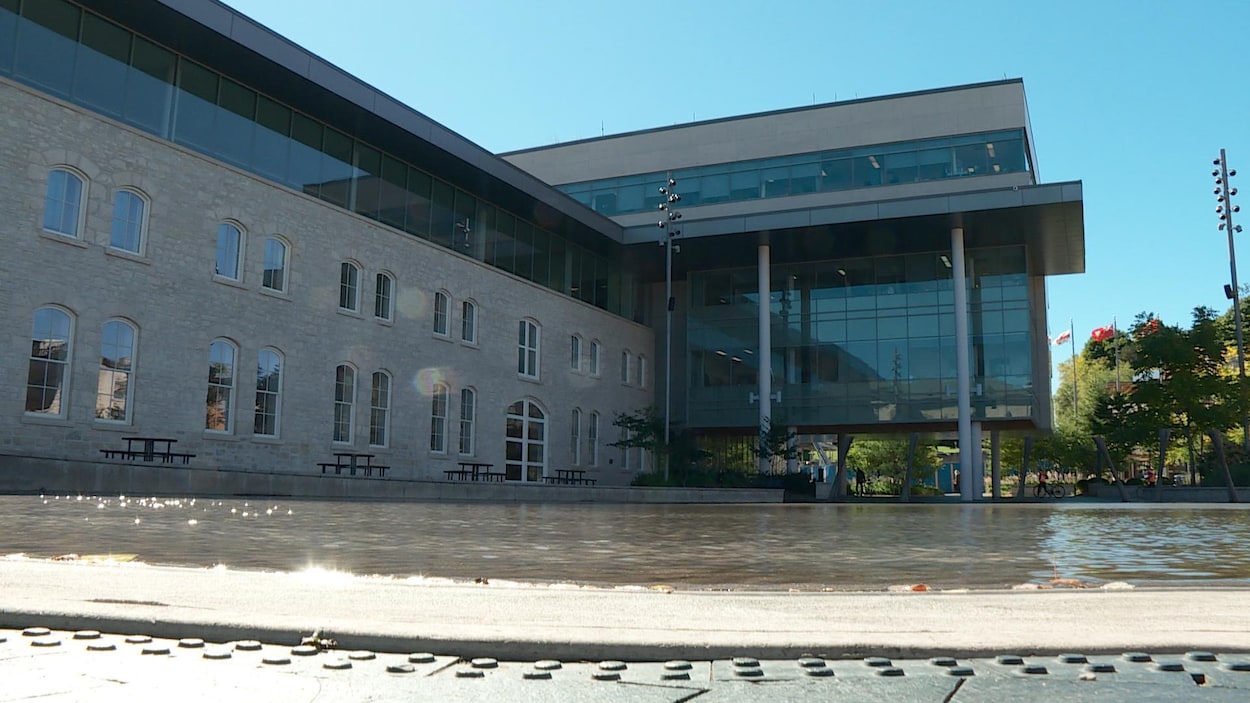 Grand bâtiment avec beaucoup de fenêtres vu en contre-plongée. On voit une étendue d'eau en face de l'édifice. Grand bâtiment avec beaucoup de fenêtres vu en contre-plongée. On voit une étendue d'eau en face de l'édifice.
