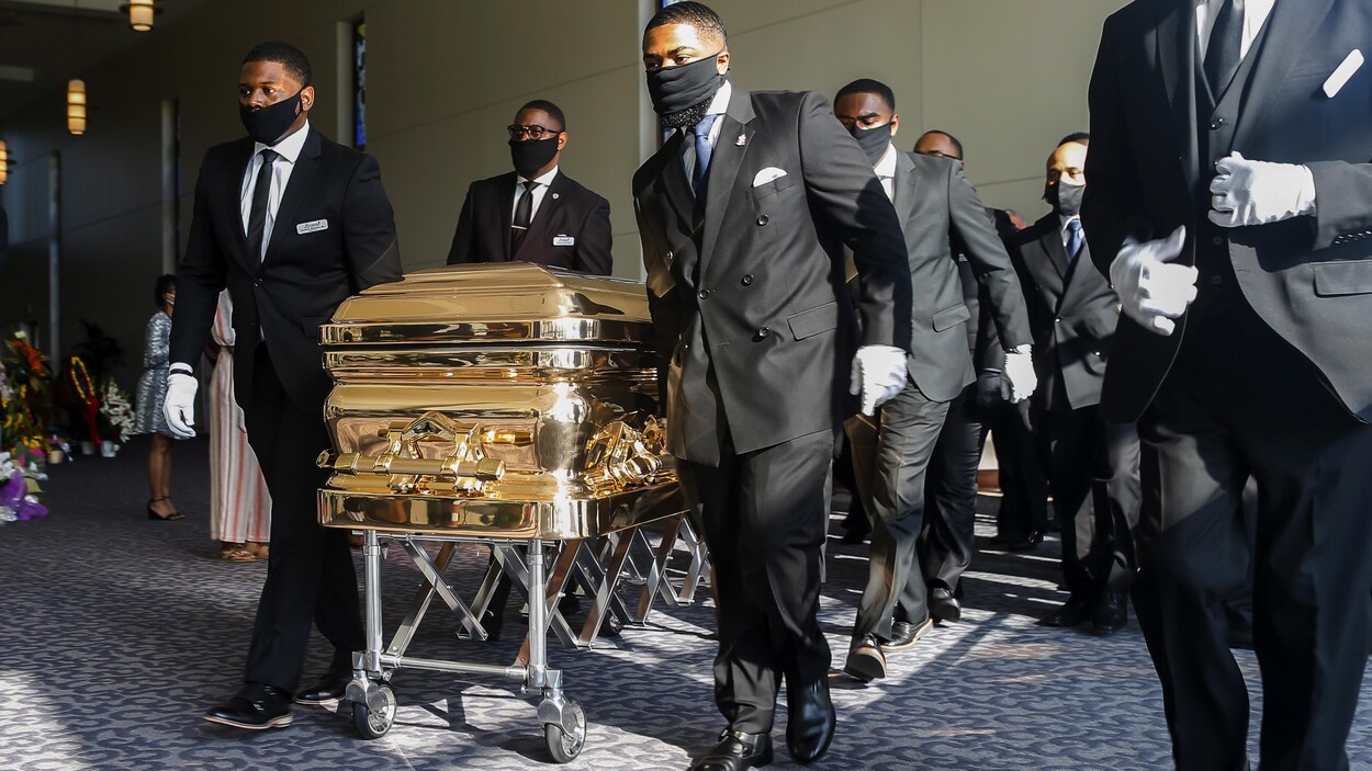 Des hommes noirs tirent son cercueil doré.