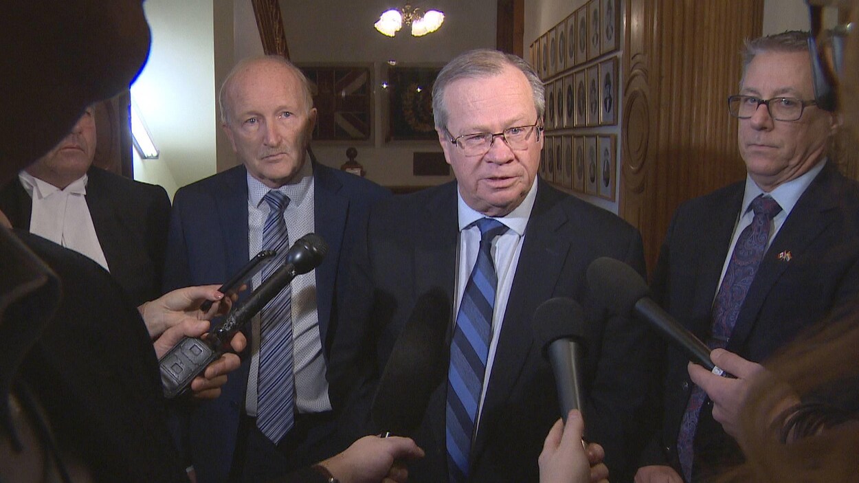 Hugh Flemming et trois autres hommes devant les micros des journalistes.