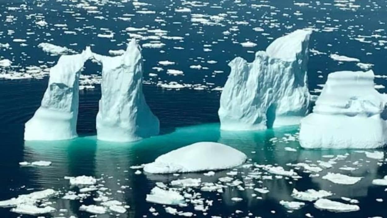 Un iceberg à quatre pointes dans la mer près de White Bay, avec de l'eau turquoise qui l'encercle.