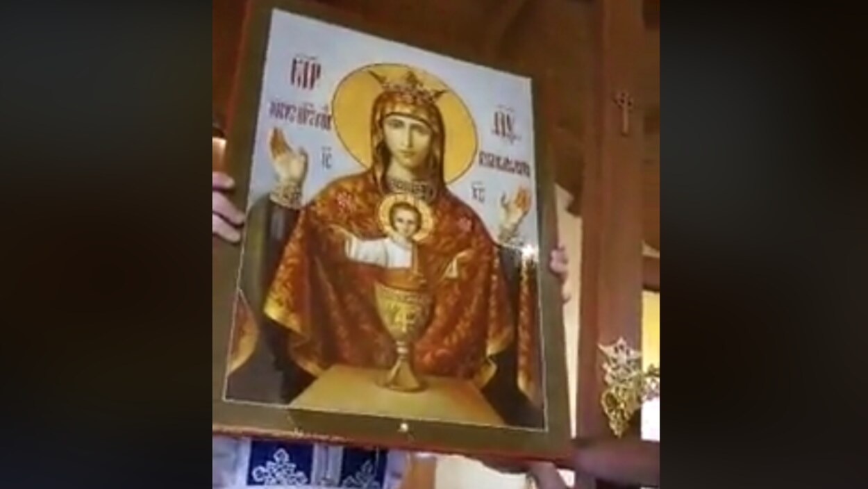 Photo des mains d'une personne qui tiennent une icône brune de la Vierge Marie.